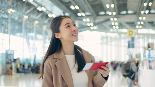 Asian young woman passenger checking depature boarding pass in airport.