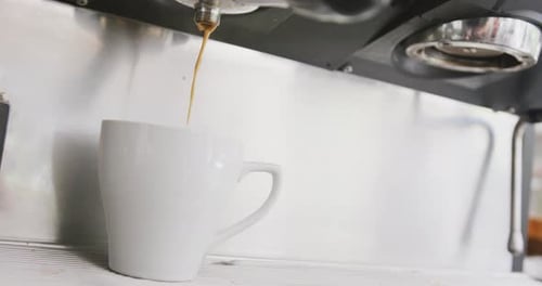 Close up of working coffee machine pouring fresh coffee into cup at cafe