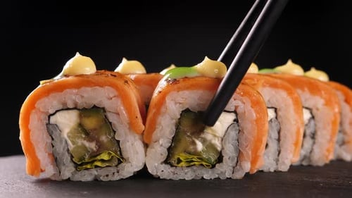 Delicious Sushi Rolls with Salmon Taken by Chopsticks