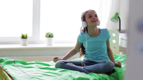 Happy girl listening to music on bed
