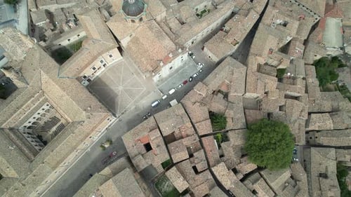 Overhead aerial view of a historic town square with adjacent narrow streets, surrounded by tightly p