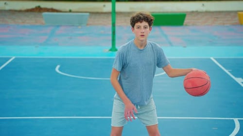 Teen Dribbling Basketball on Blue Urban Court