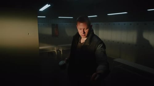 Homme adulte avec tasse à café entrant dans le vestiaire de la salle de sport et ouvrant l'armoire avant l'entraînement