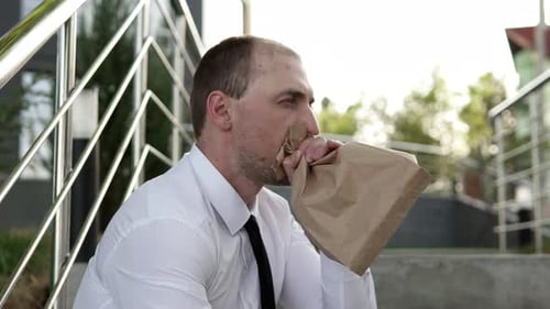 Un homme frustré qui essaie de se calmer respire dans un sac en papier.