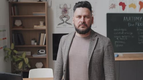 Teacher in Classroom Stands near Blackboard