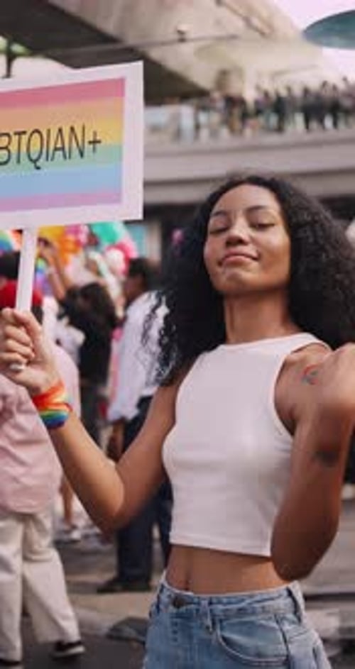 Vertical clip. A young black woman shows off her homosexual identity in a pride parade.