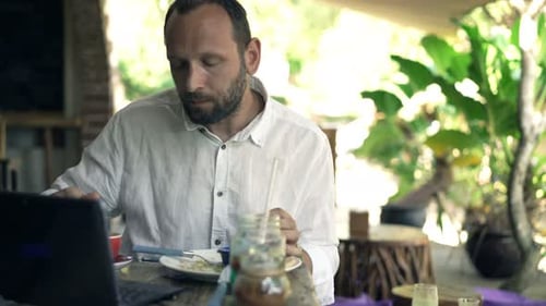 Young Man Using Laptop, Eating Meal and Drinking Coffee in Cafe Adult
