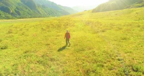 Flight Over Backpack Hiking Tourist Walking Across Green Mountain Field Huge Rural Valley at Summer