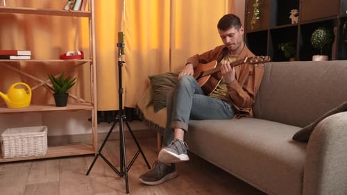 Young Adult Plays Guitar For Smartphone Recording