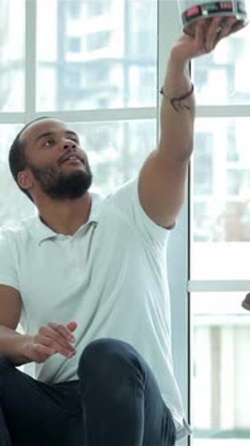 Cheerful Man Reaching for a Paint Can During Apartment Renovations