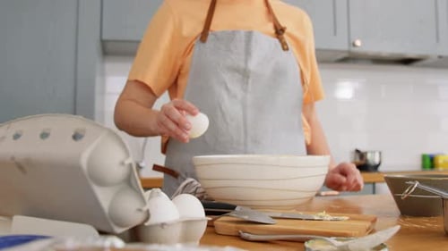 Woman Cracking an Egg into a Mixing Bowl