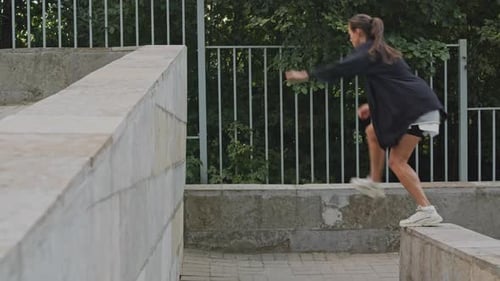 Female Athlete Jumps Over Concrete Wall Doing Parkour