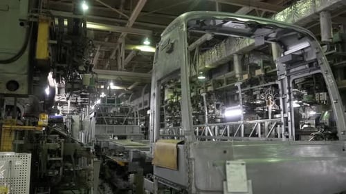 Plan large d'une chaîne de montage d'autobus montrant les différentes étapes de la construction du châssis et du soudage