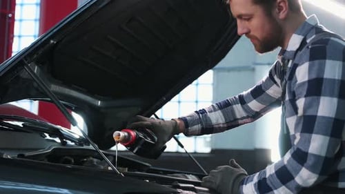 Neues Öl einfüllen. Mann repariert das Auto an einer Tankstelle