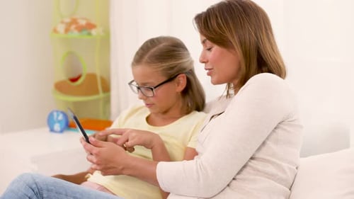 Mother and Daughter Using Tablet on Sofa at Home