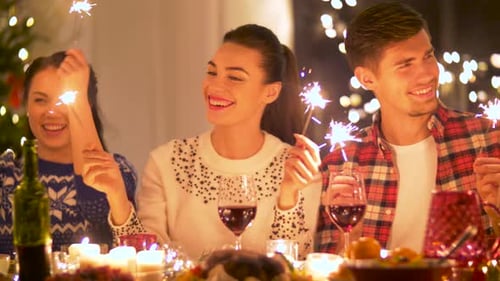 Friends celebrate together with sparklers at a candlelit table