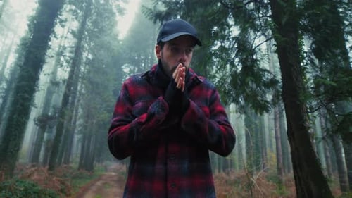Man in a Red Plaid Shirt in the Woods Rubs His Hands in the Cold