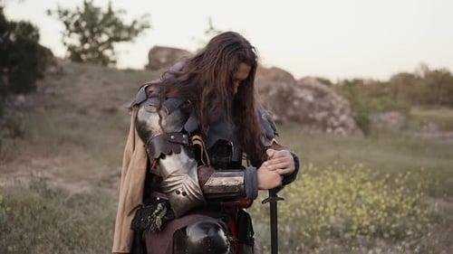 Cavaleiro medieval se ajoelha em oração no campo