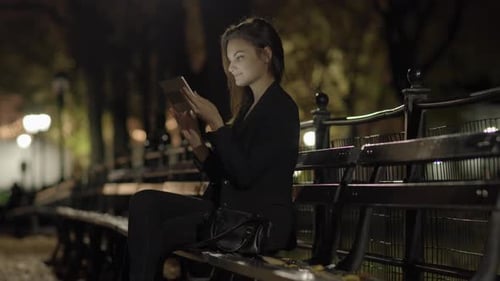 Young Woman Using Tablet Computer In The Park At Night
