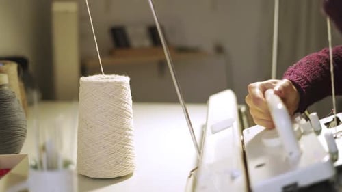 Female hands skillfully knitting fabric on a modern weaving machine in workshop