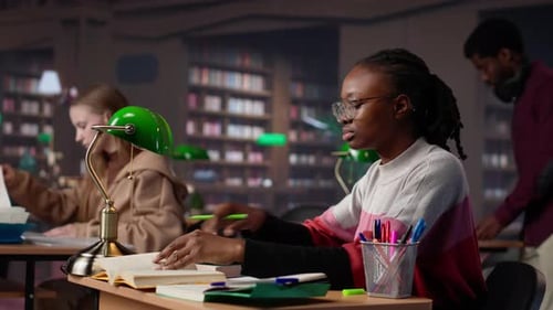 University Student Engrossed in Texting with Classmates at the Library