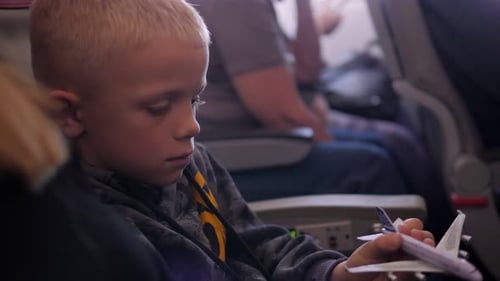 A Eightyearold Child Plays with a Toy Airplane on an Airplane During a Flight