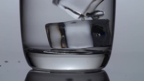 Close Up Of Three Ice Cubes Falling In A Glass Of Drinking Water On The Light White Background