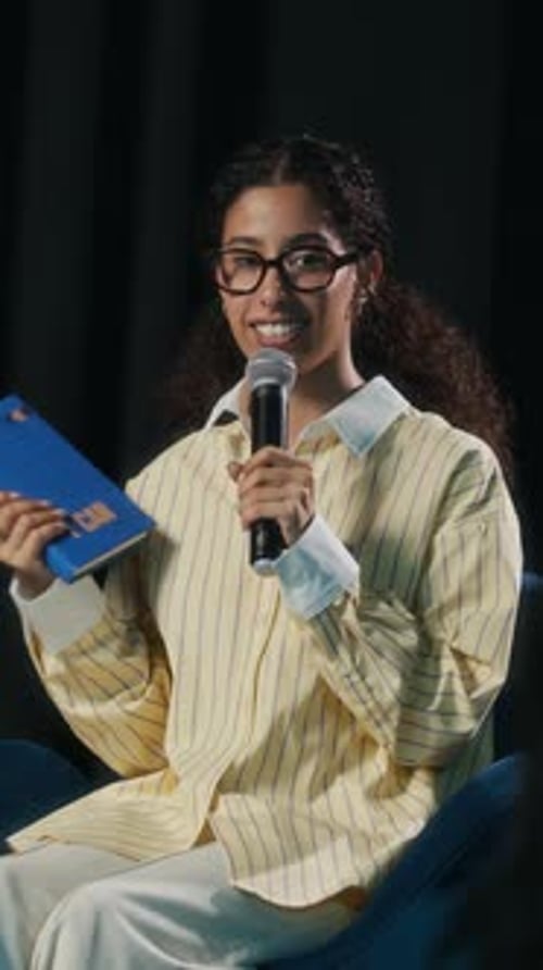 Vertical of Young Biracial Female Author Presenting Her Book on Stage