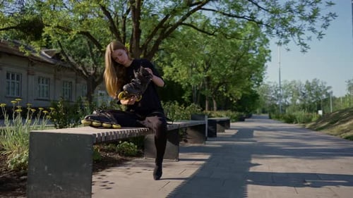 young beautiful girl in the park takes out and looks at roller skates before skating training