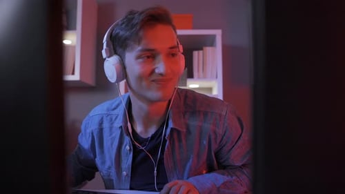 Smiling Young Adult at Computer with Headphones