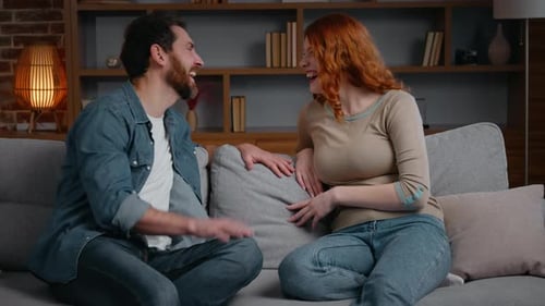Couple Laughing and Talking While Sitting on Couch