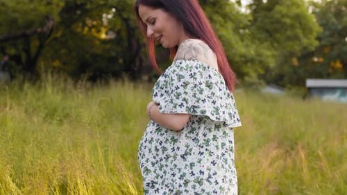 Pregnant Woman Poses Happily in a Field