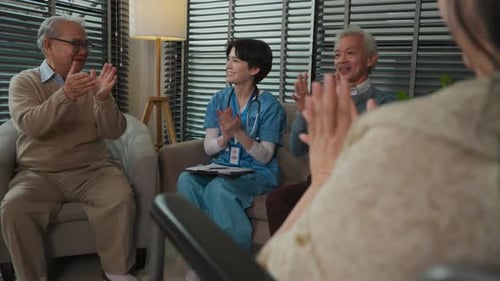 Cheerful Seniors and Nurse Clapping in Living Room