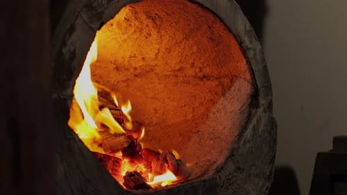 Gloved Hand Adjusts Charcoal in Industrial Forge