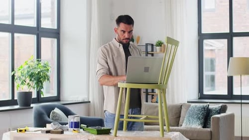 Man Using Laptop on Chair in Bright Home