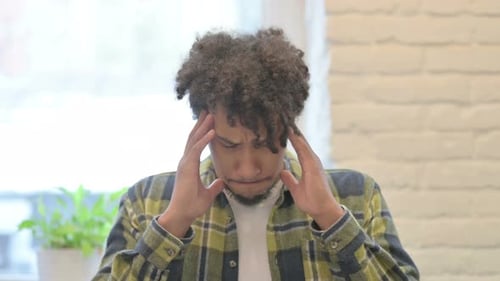 Man Rubs Temples, Appearing to Have a Headache
