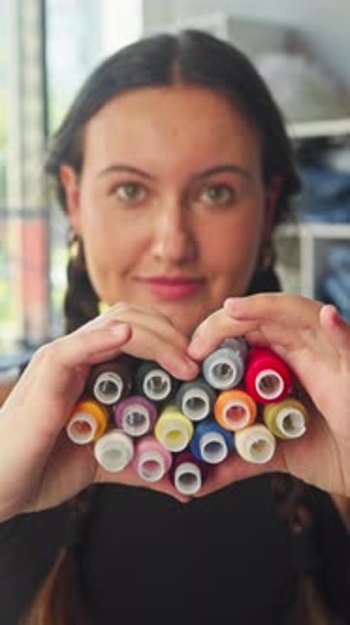 Woman Holds Heart Shape with Colorful Thread Spools