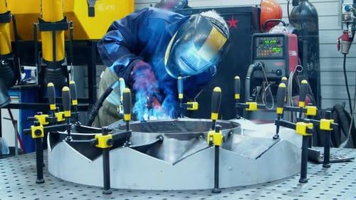 Man Welding Metal with Protective Gear in Factory