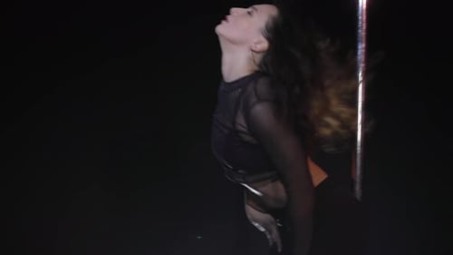 Woman Performing Pole Dance in Dimly Lit Room