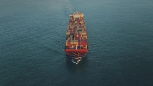 Drone shot of large industrial cargo container ship in the middle of the blue ocean