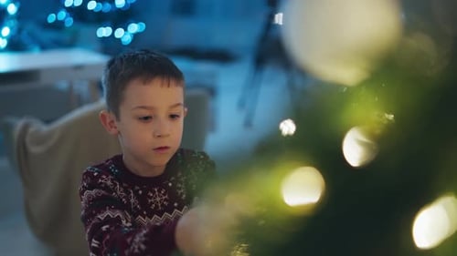 Boy Decorating Christmas Tree at Home at Night