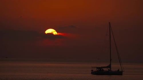 Sailboat Silhouetted Against Vibrant Ocean Sunset