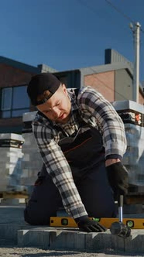 Construction Worker Hammering Pavement Brick in City
