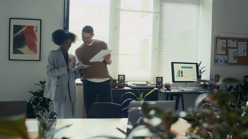 Black Woman Discussing Project with her Colleague, Standing in Biophilic Office