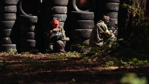 Paintballspieler trägt Schutzmaske und schießt auf Spieler in Schutzkleidung