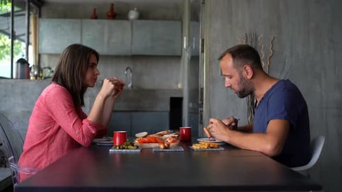 Couple eating lunch at table in modern kitchen