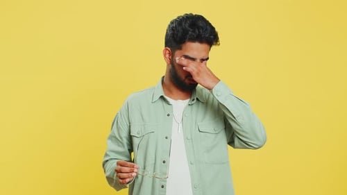 Man Removes Glasses, Rubs Eyes, and Looks Relieved