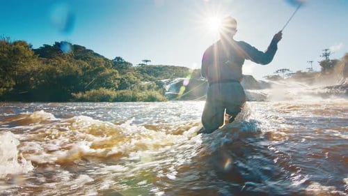 Man Fly Fishing in Rushing River on Sunny Day