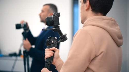 Two professional photographers shooting in an office using cameras on a tripod and stabilizer
