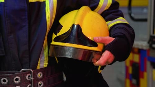 Feuerwehrmann mit Helm in den Händen steht aus nächster Nähe am Bahnhof